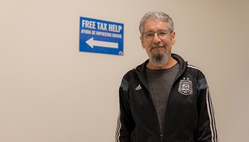 Man standing in front of free tax help sign