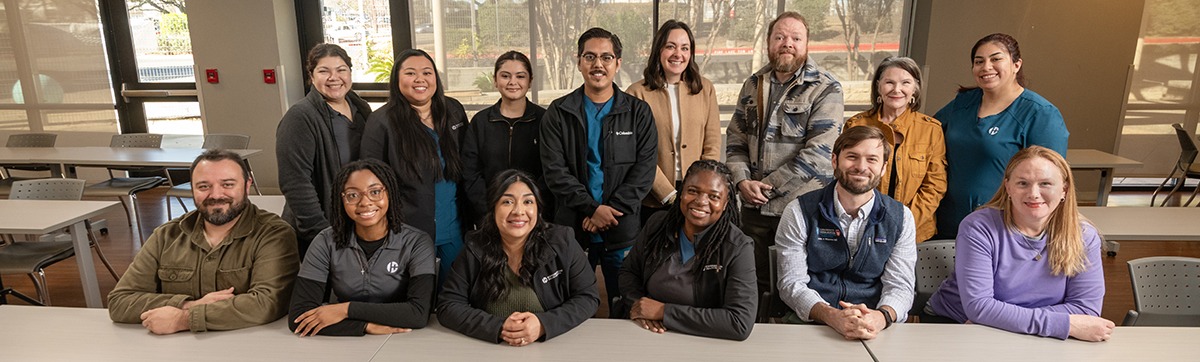 a group of 14 adults in two rows posing for a picture