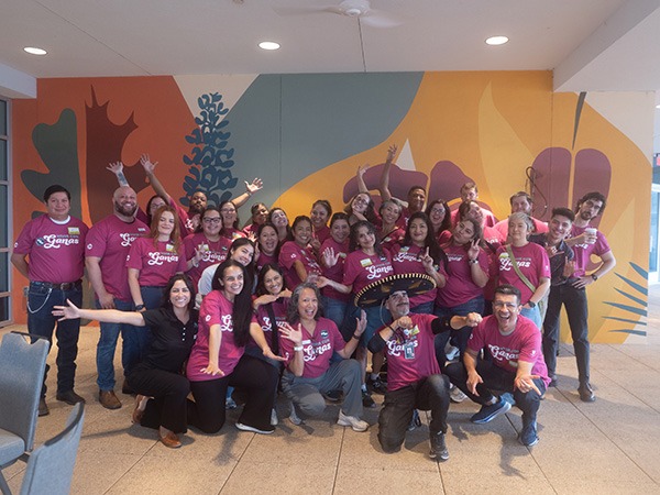 About 30 people in pink shirts posing for a picture