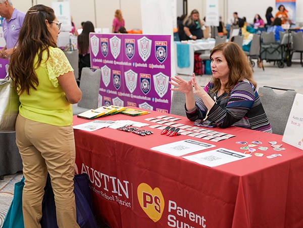 a woman sitting behind a vendor booth and a woman standing in front talking to her