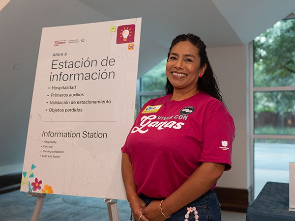 A woman in a pink shirt standing next to a posterboard